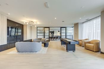 A spacious living room with a grey sofa and a black coffee table.